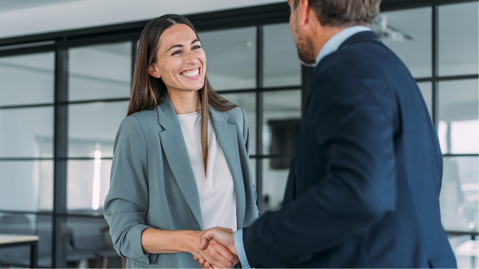 /_cms/webroot/Two business people shake hands in an office.